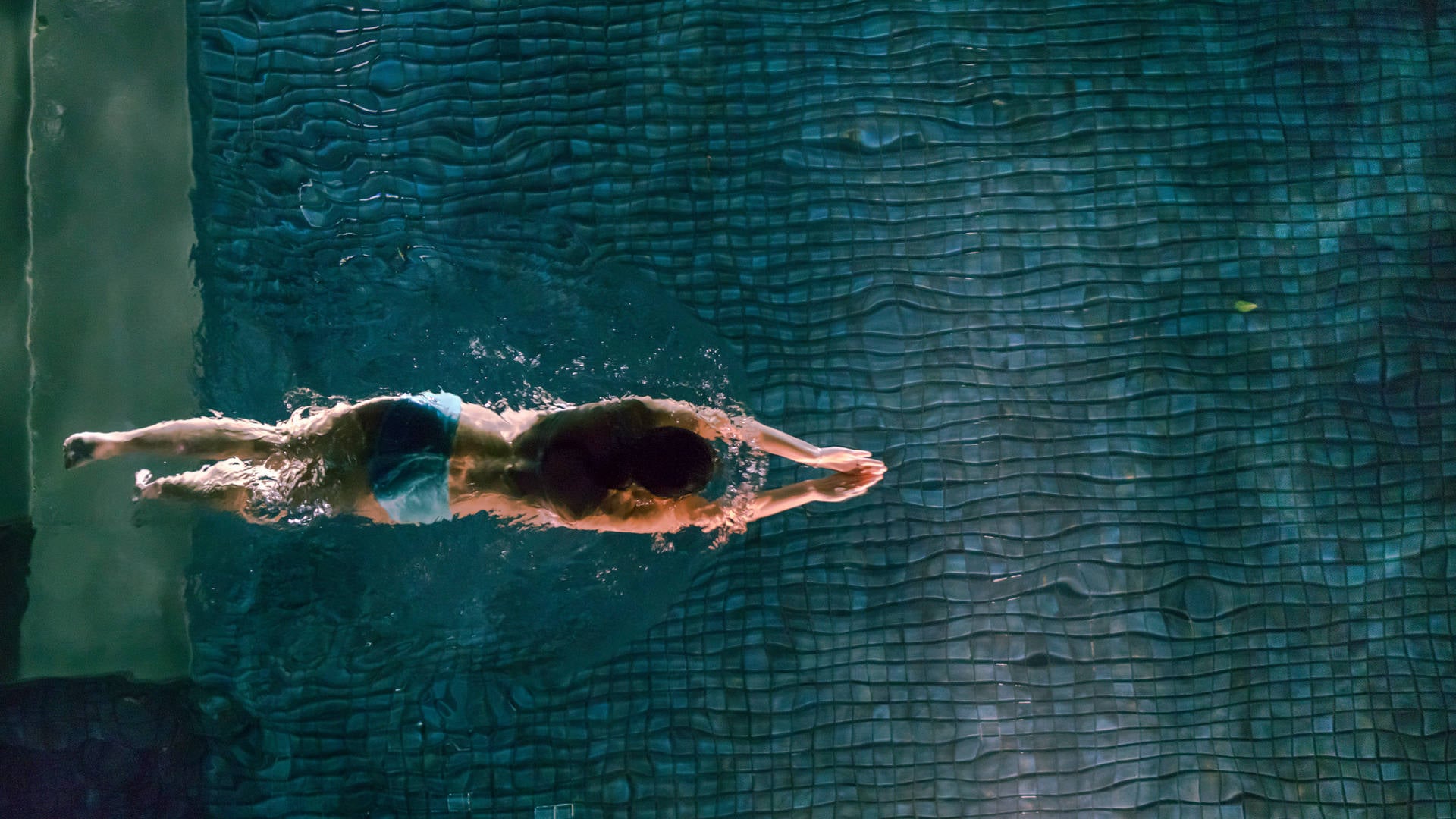 Personne nageant dans une piscine éclairée.