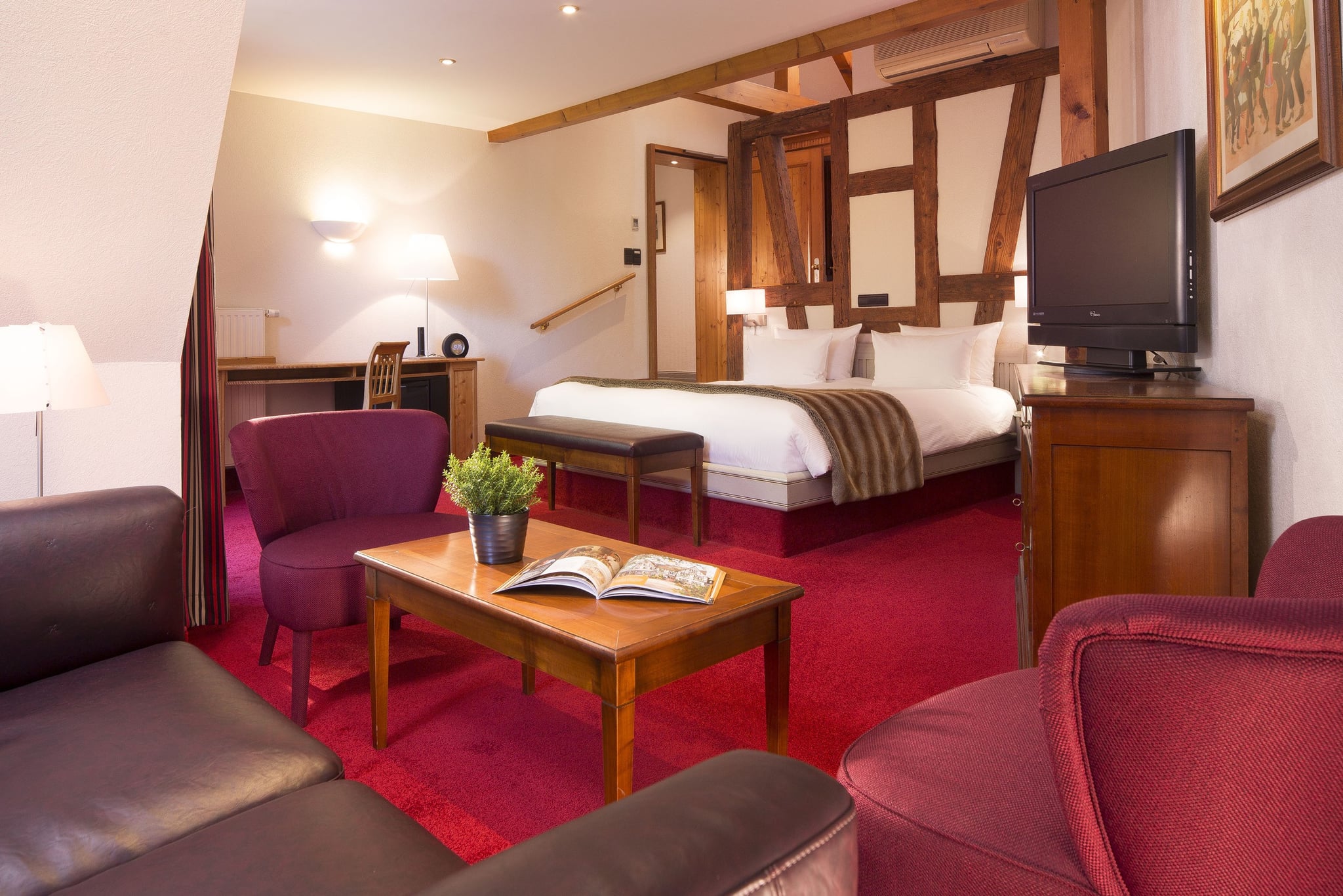 Chambre d'hôtel confortable avec lit double et fauteuils.