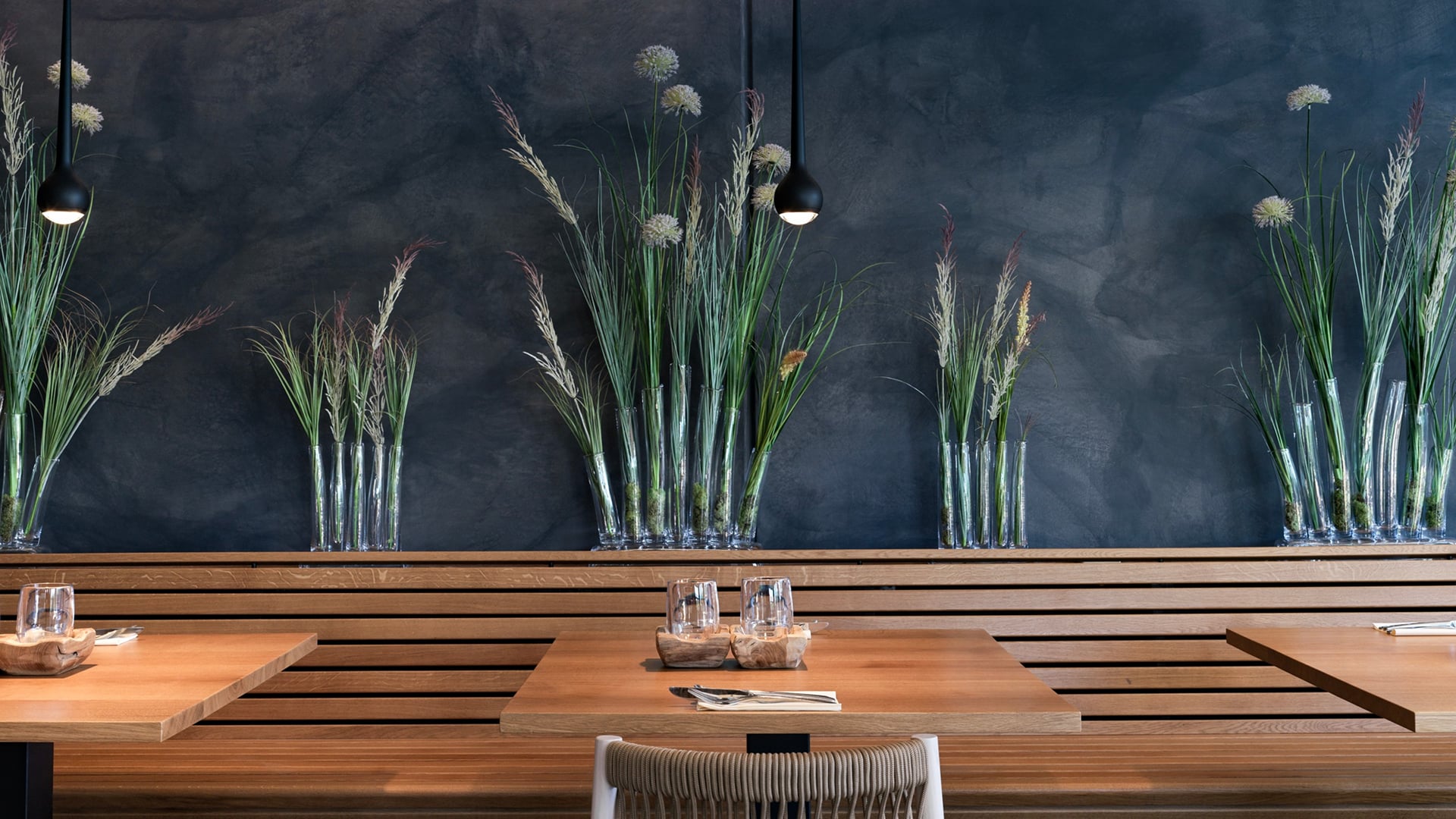 Restaurant avec tables en bois et plantes décoratives.