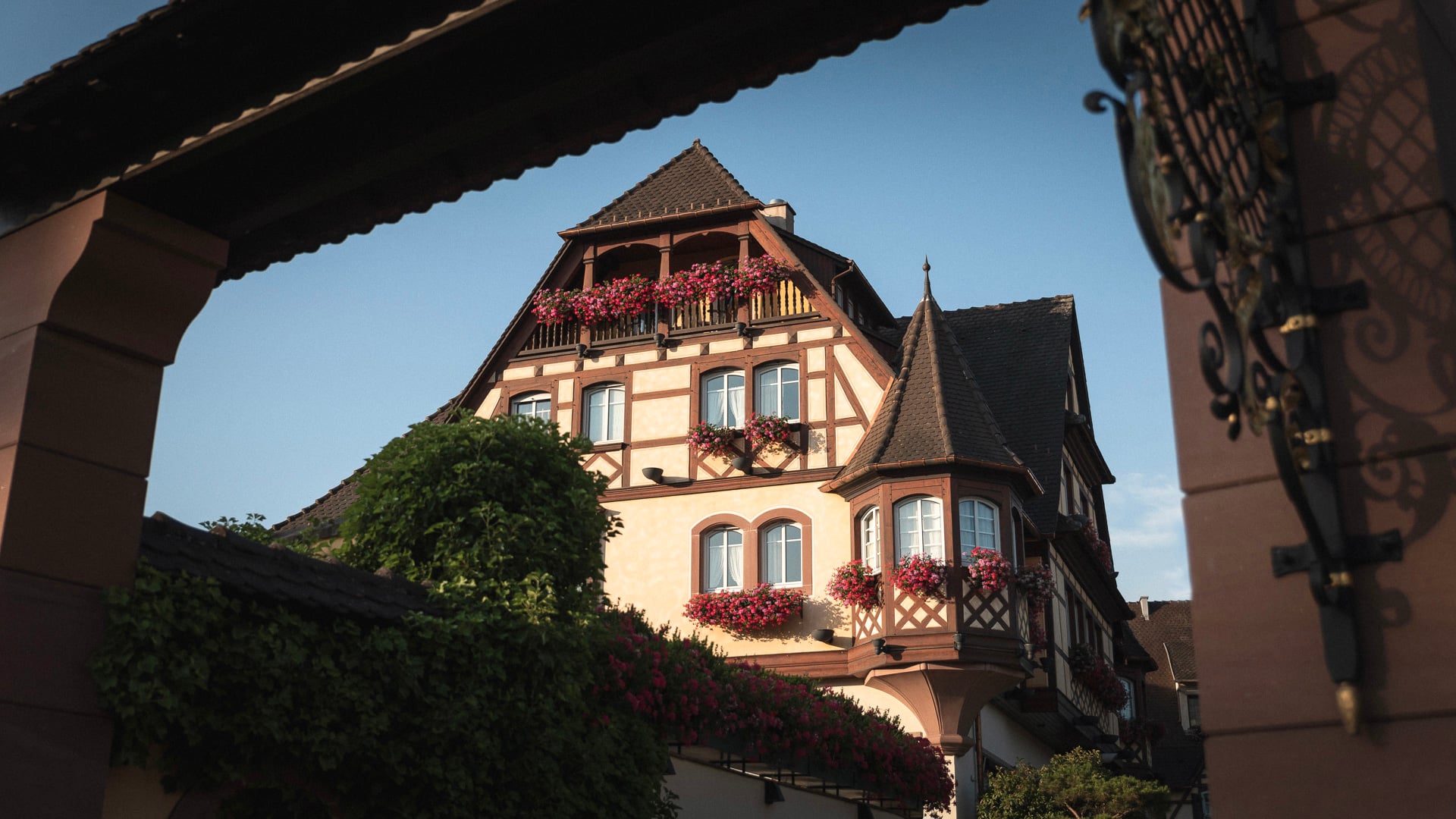 Maison alsacienne traditionnelle avec fleurs, ciel bleu.