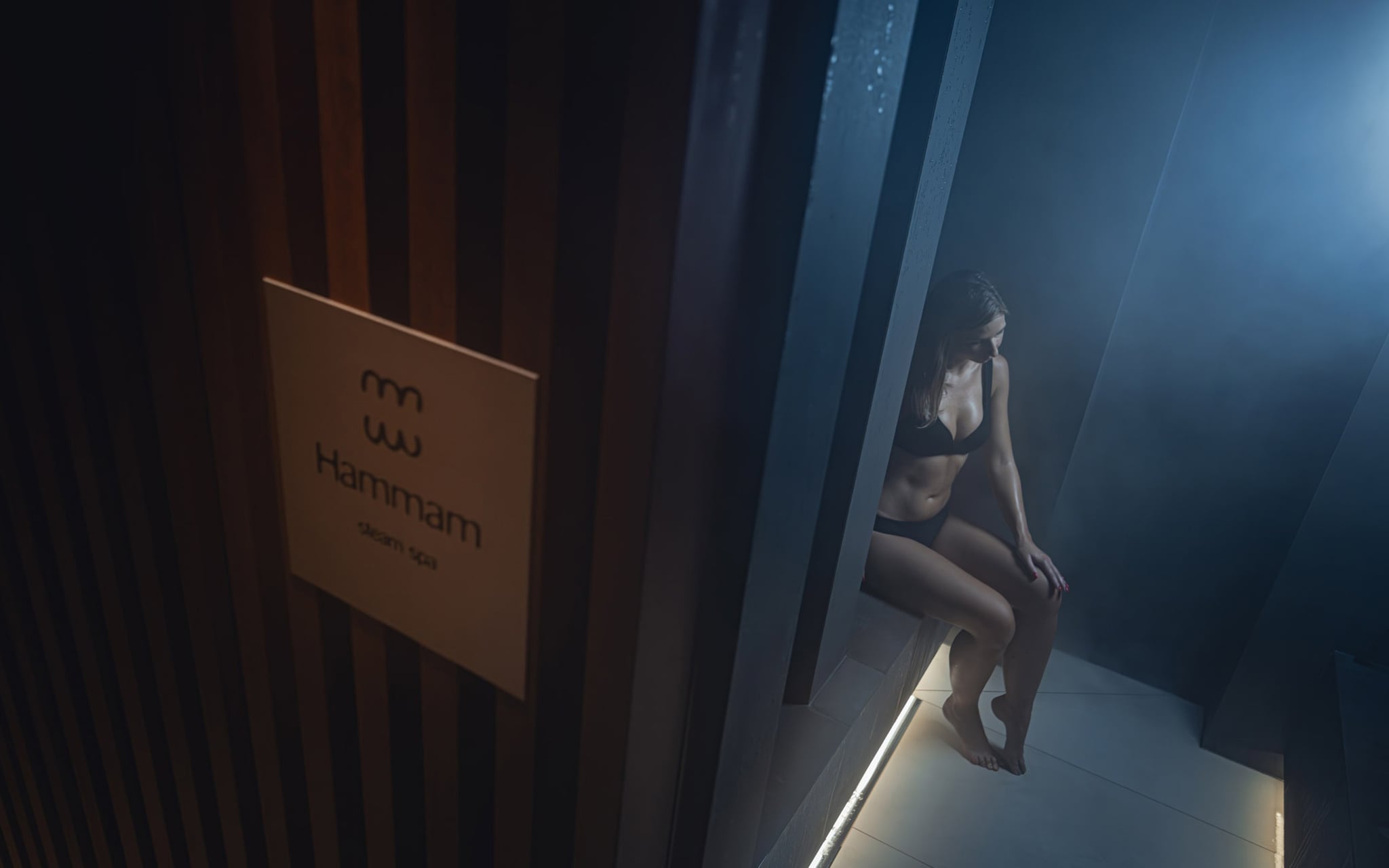 Femme dans un hammam enveloppée de vapeur.