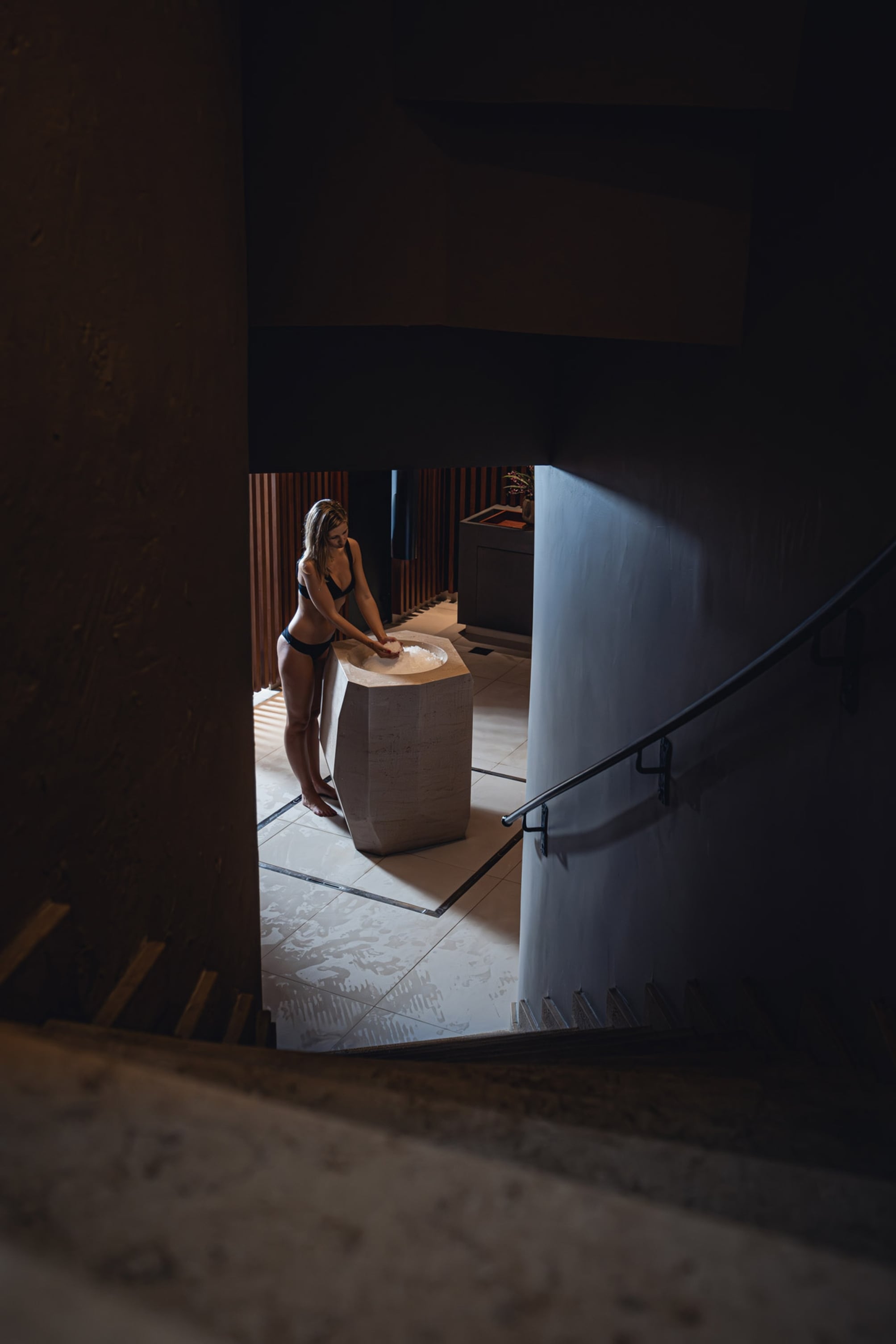 Femme debout près d'un lavabo en pierre.