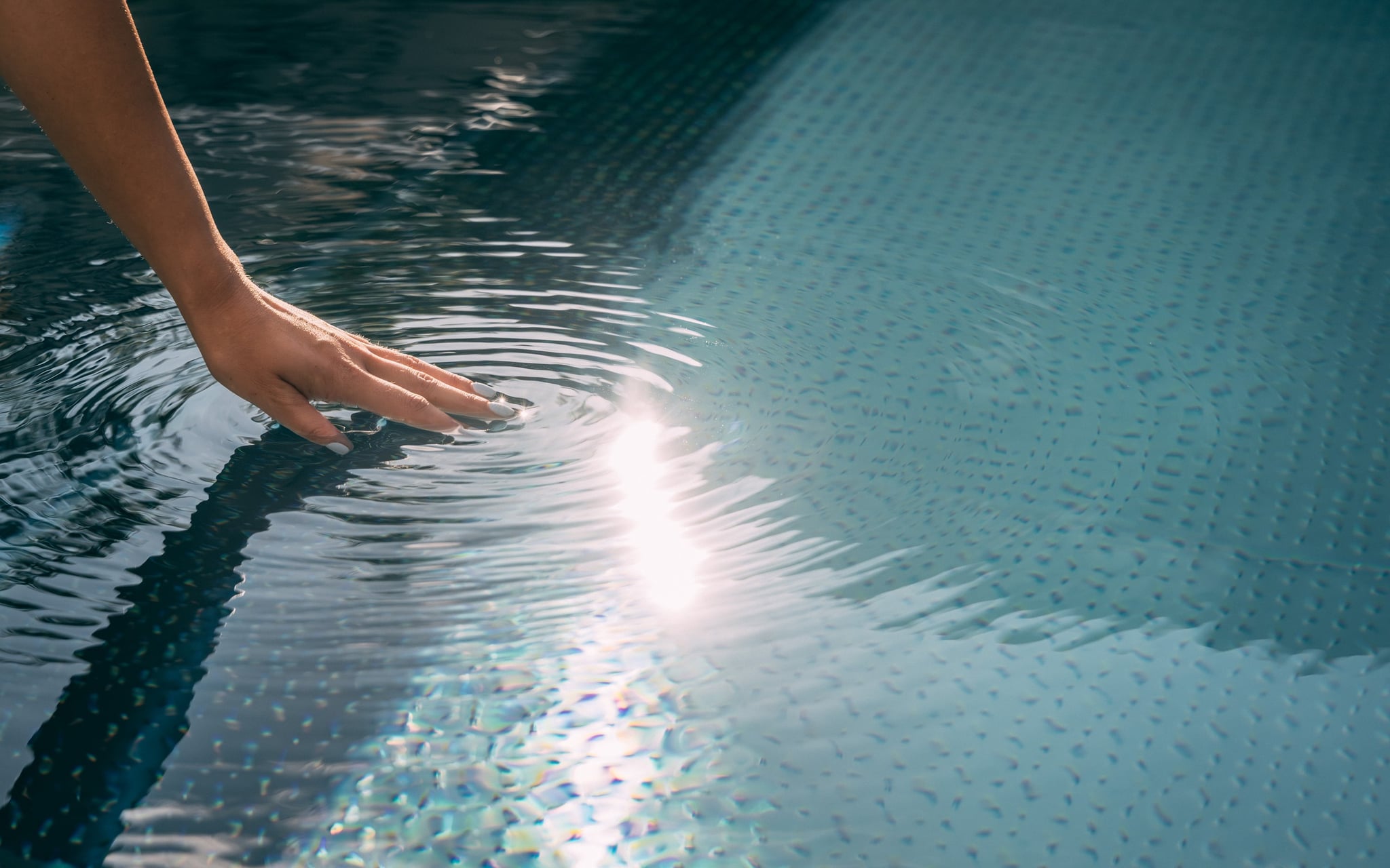 Main touchant l'eau créant des ondulations