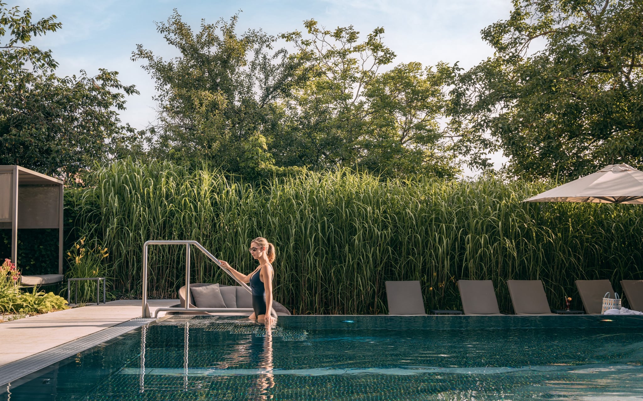 Femme dans une piscine entourée de verdure.