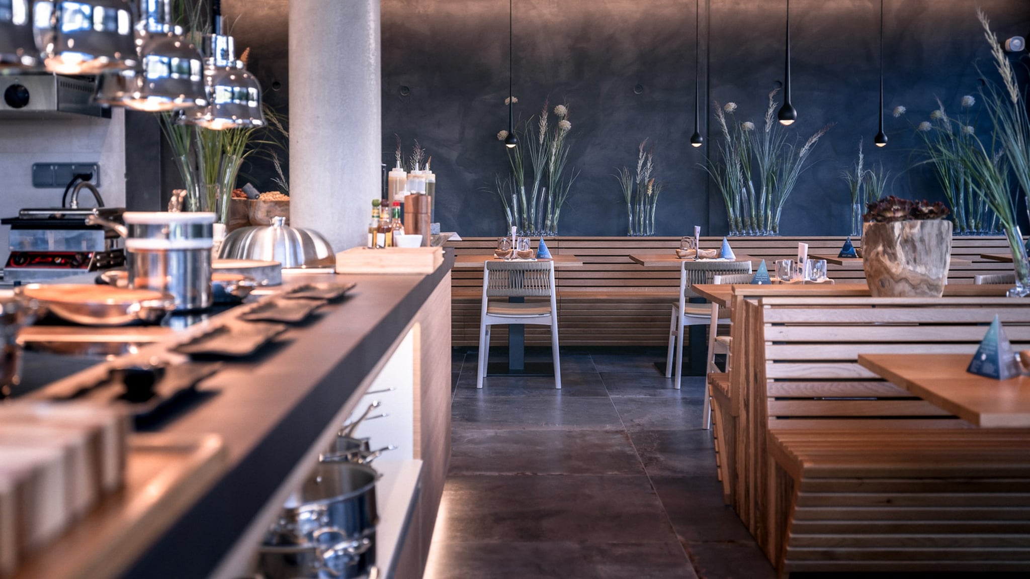 Restaurant moderne avec tables en bois et décoration végétale.