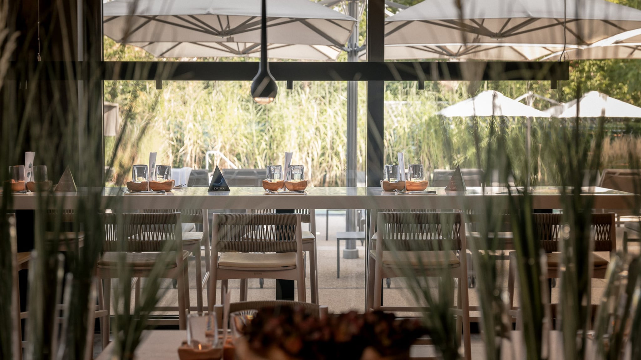 Restaurant moderne avec table dressée et parasols.