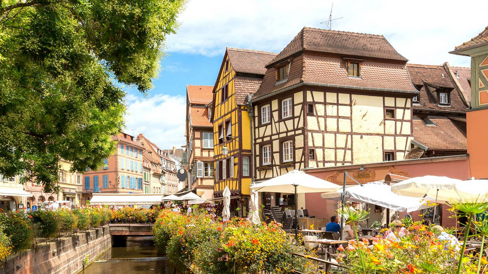 Maisons traditionnelles en bord de rivière, fleurs colorées.