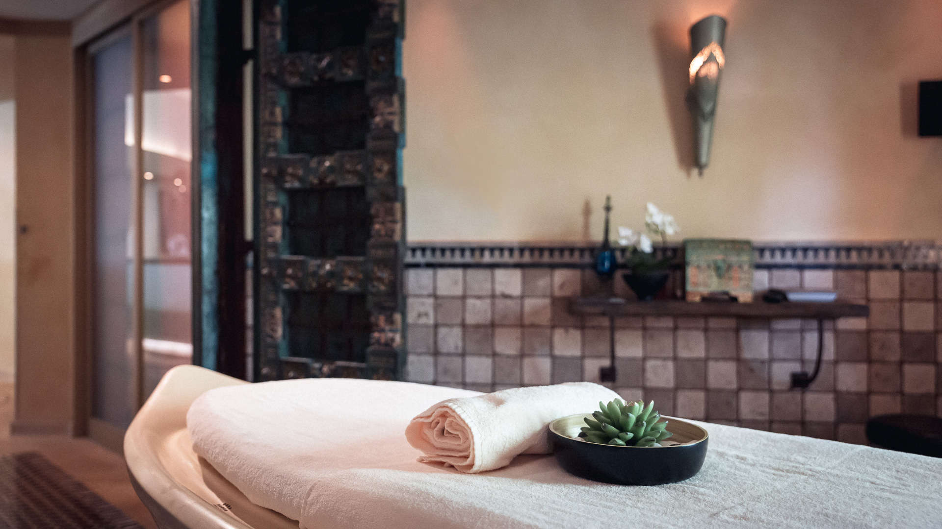 Table de massage avec serviette et plante.