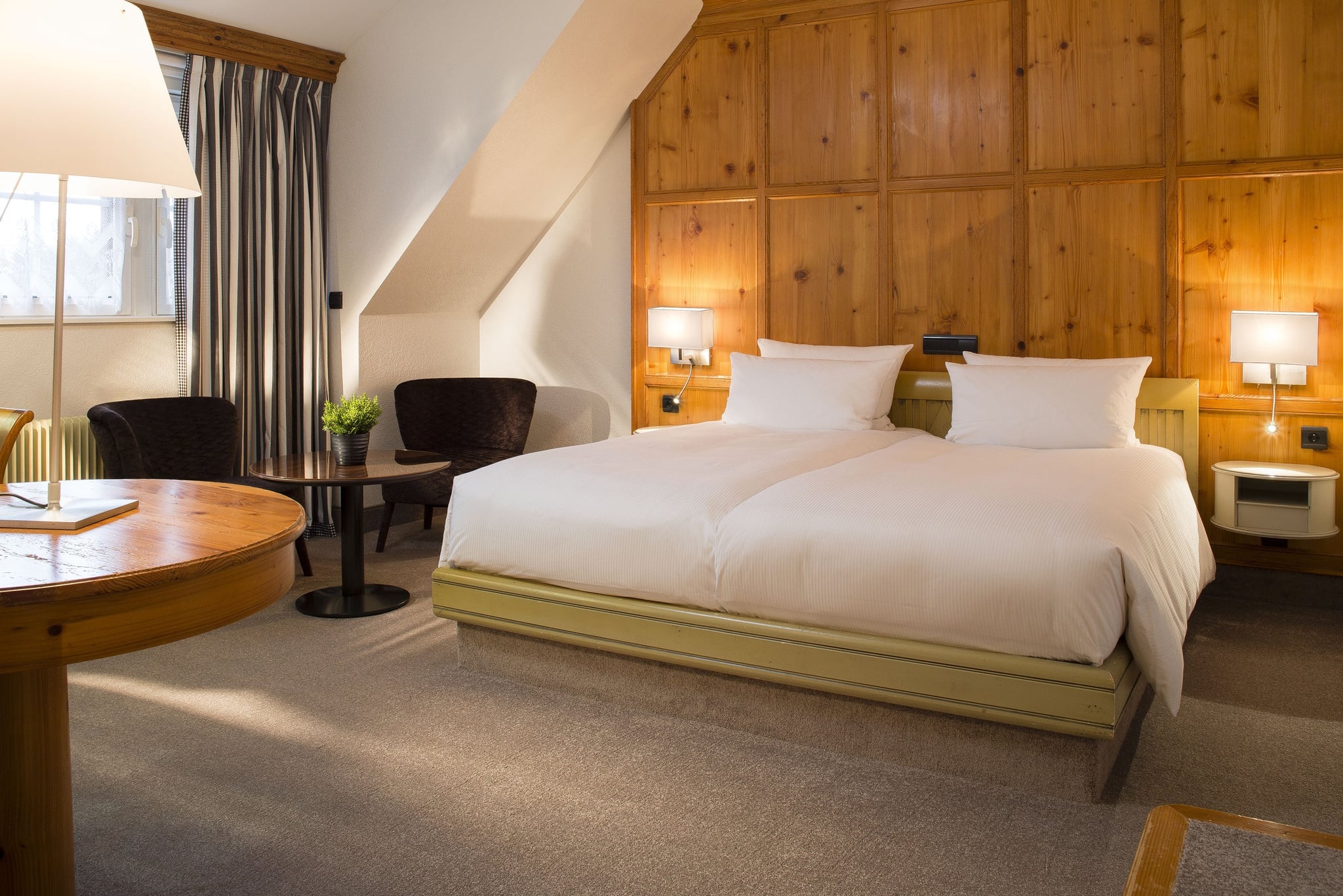 Chambre d'hôtel avec lit double et fauteuils.