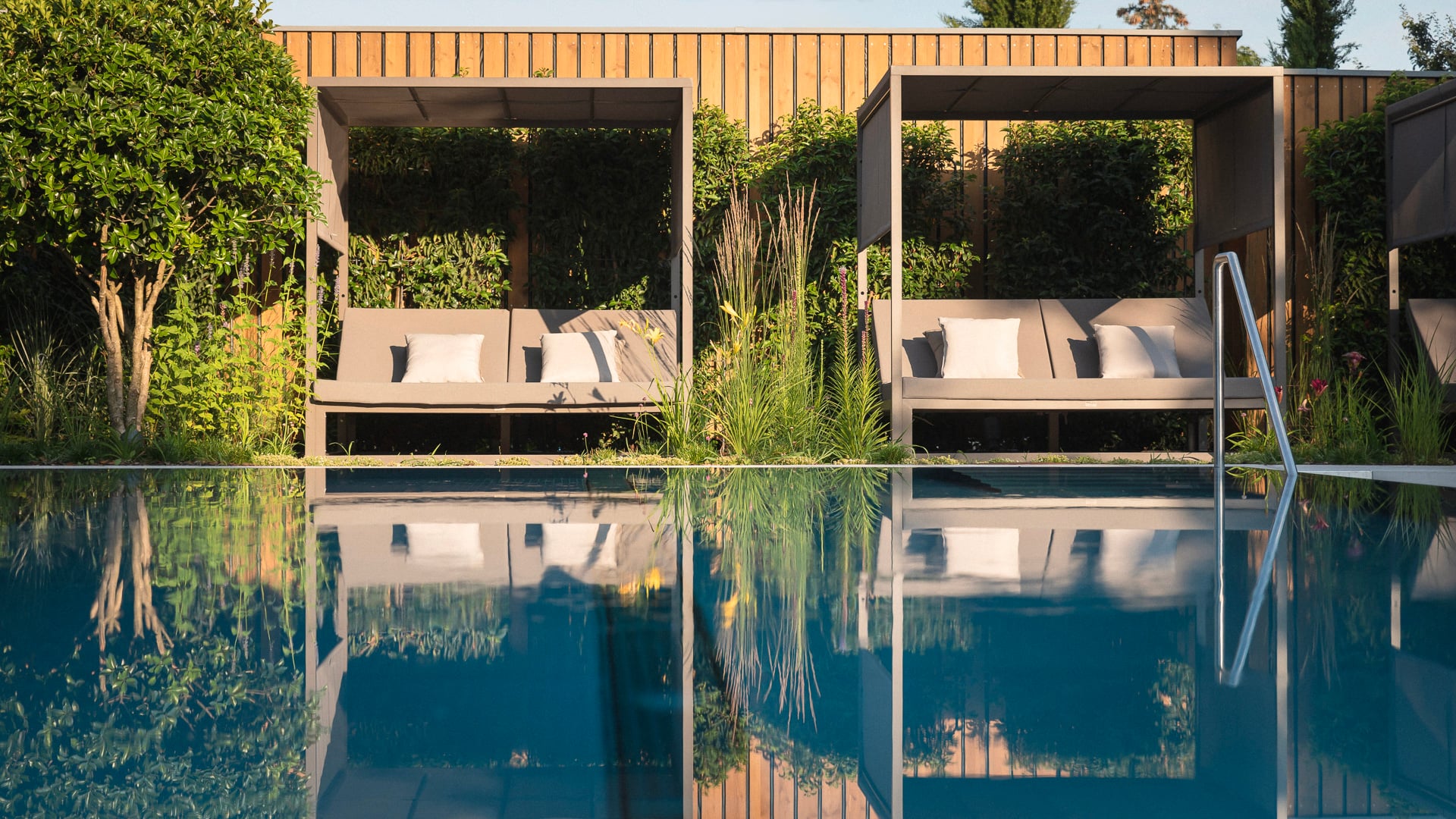 Piscine avec lits extérieurs et végétation luxuriante.