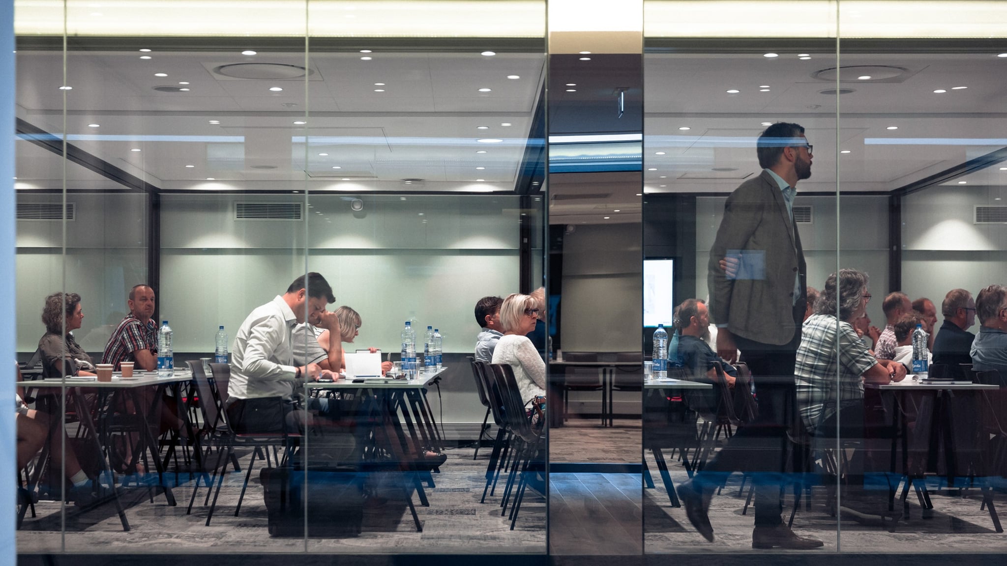 Personnes assistant à une réunion dans une salle.