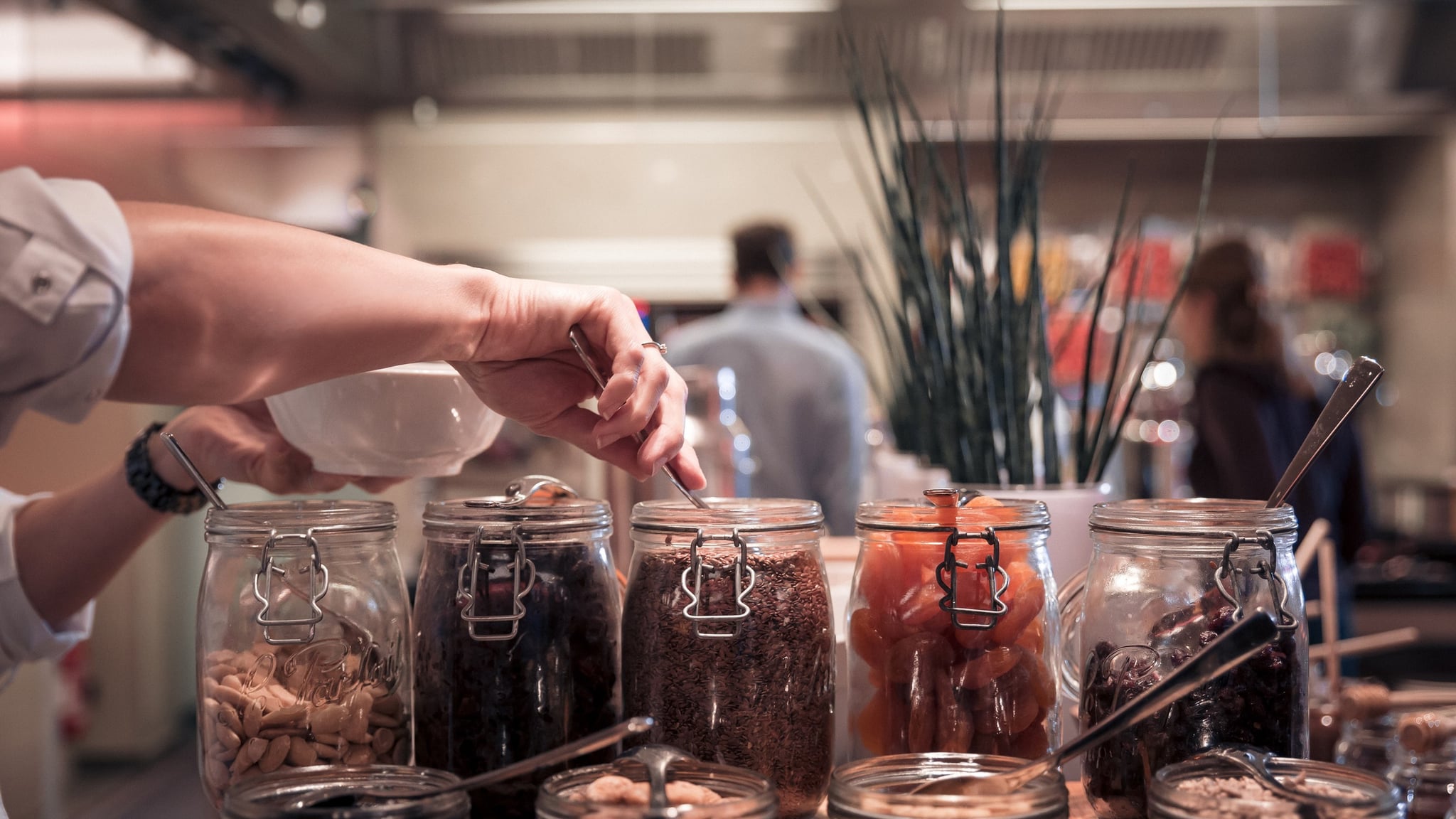 Personne choisissant des aliments dans des bocaux en verre.