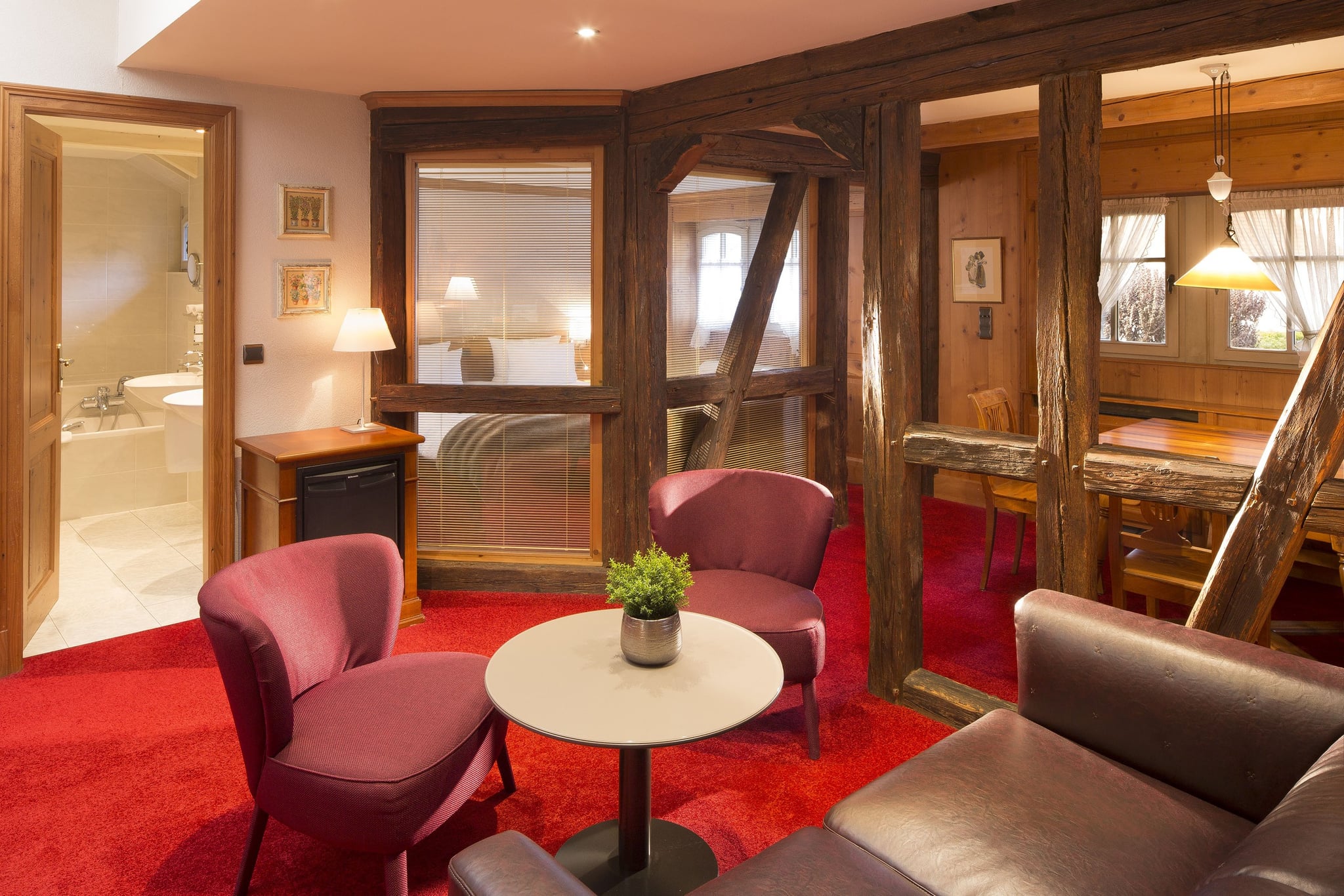 Salon chaleureux avec fauteuils rouges et boiseries.