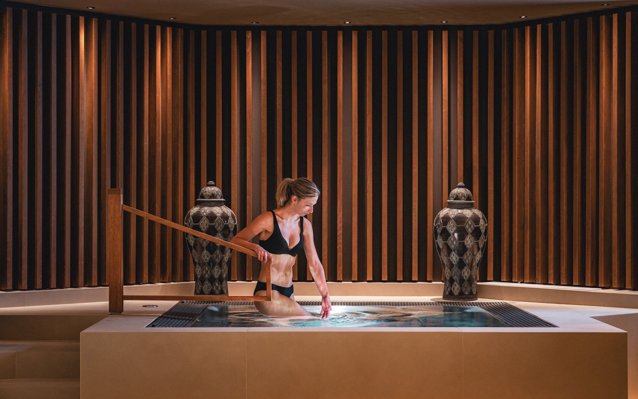 Femme entrant dans un bain chaud élégant, décor luxueux.