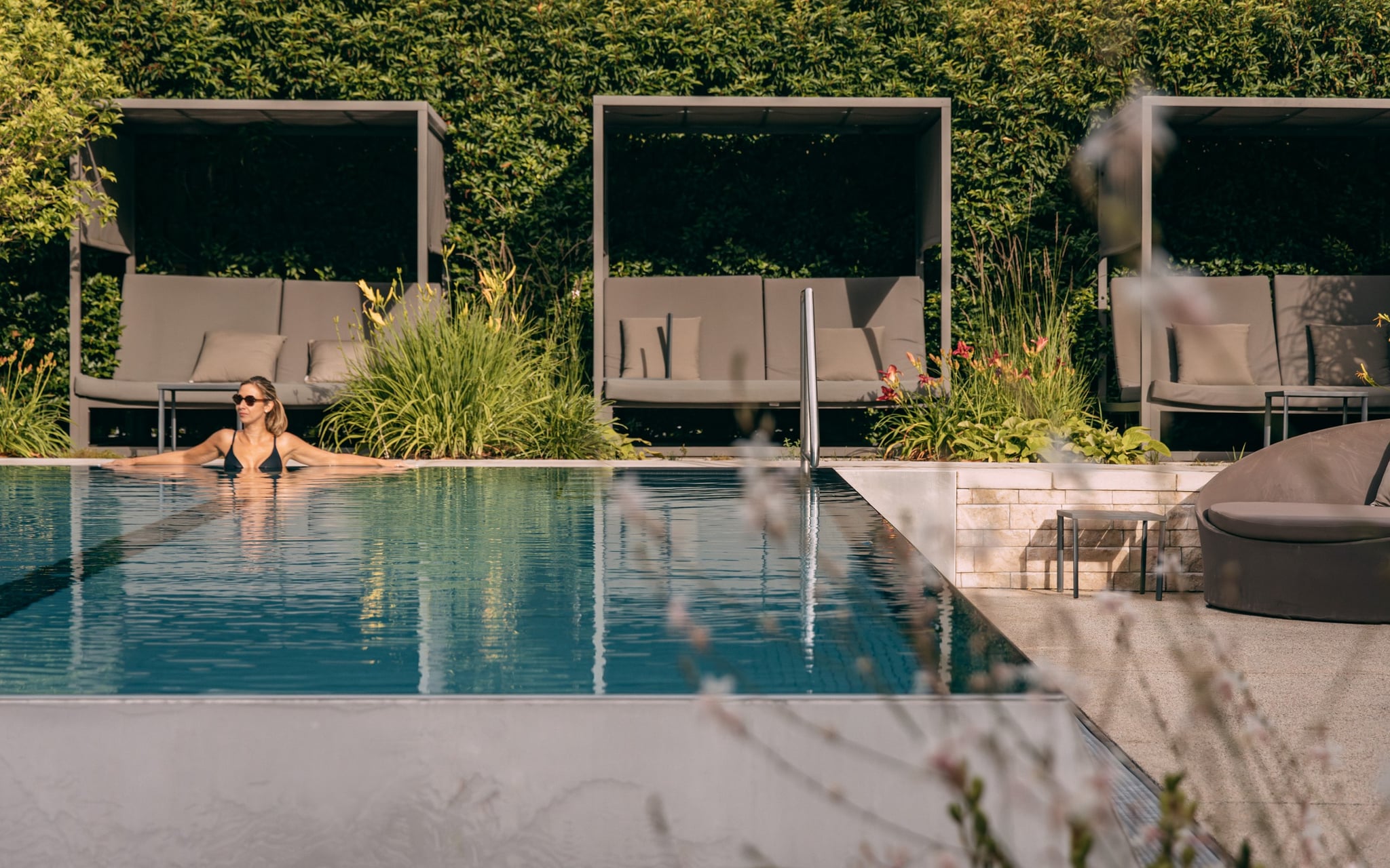 Personne dans piscine devant transats.